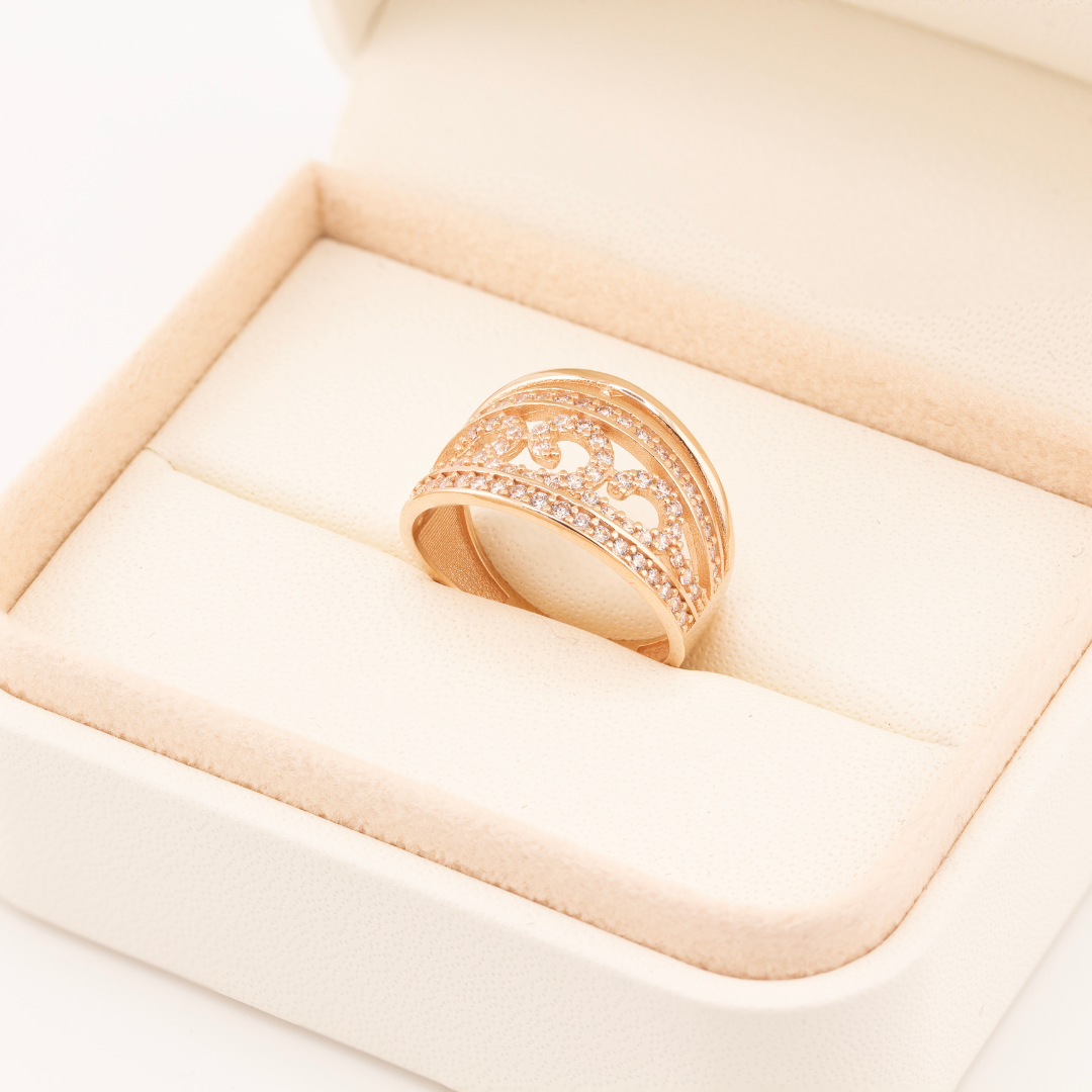 Raudono aukso žiedas su banguotu ornamentu centre, apsuptu viršutine ir apatine cirkonių juostomis