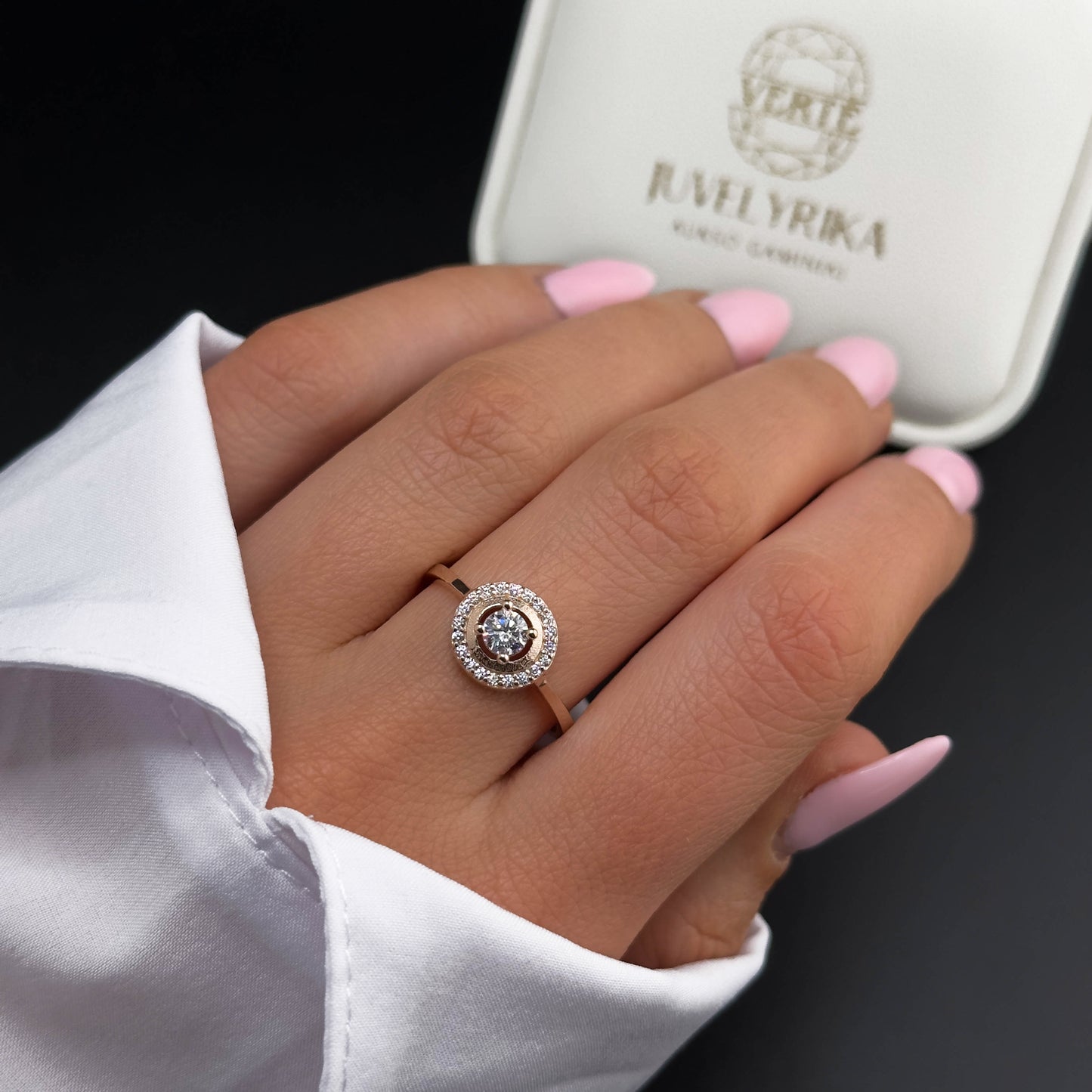 Rožinio aukso žiedas su baltu centriniu cirkoniu ir apvalia mažų cirkonių inkrustacija