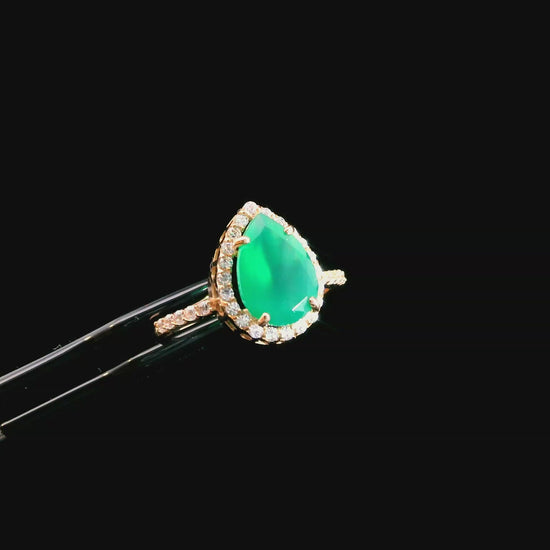 Šis auksinis lašo formos žiedas iš 585 raudono aukso yra tikras elegancijos simbolis. Žiedo centre esantis natūralus akmuo ne tik suteikia ypatingą grožį, bet ir pabrėžia kiekvieno akmens unikalumą. Aplink pagrindinį akmenį subtiliai įkomponuoti balti cirkoniai suteikia papildomo švytėjimo ir išryškina jo prabangų dizainą. Sveriantis apie 2.20g, šis žiedas ne tik traukia akį, bet ir yra maloniai lengvas bei patogus nešioti.